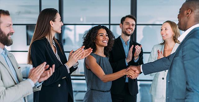 Young Black woman shakes hand with manager after being recognized at work.