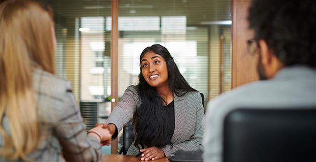 Young woman shakes hand with interviewer at a job interview.