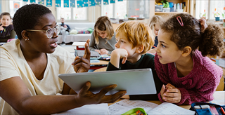 Teacher assisting students with using their tablets in class.
