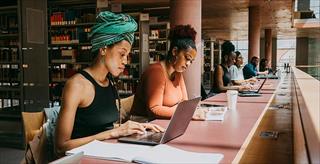 college students working on laptops in the library