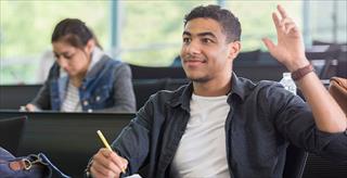 Young male college student raises his hand to ask a question in class.