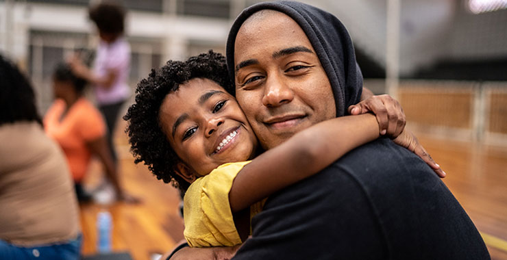 Man and child hug while looking at camera.