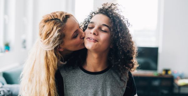 mother kissing teenage son on cheek