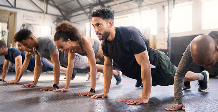 Gym with men and women exercising for muscle, cardio, and endurance.
