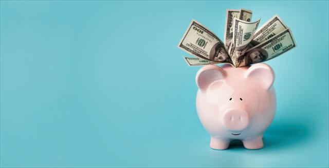 Pink piggybank stuffed with dollar bills