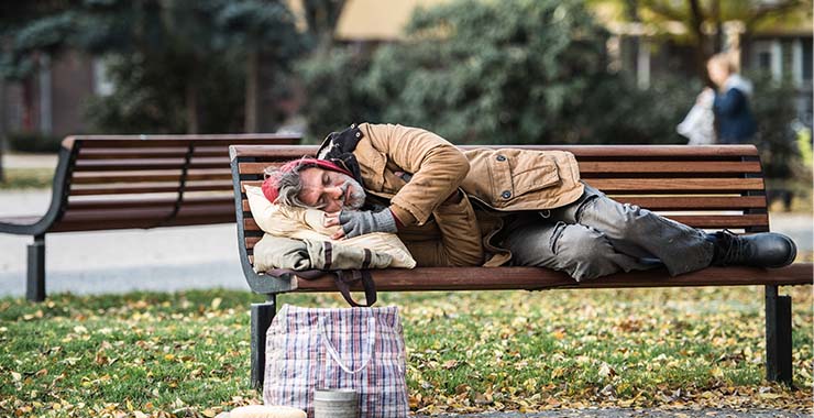 Homeless man sleeping on a bench outside