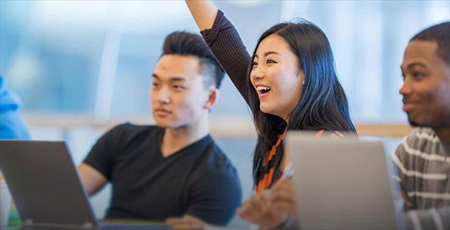 College student raises her hand during lecture.