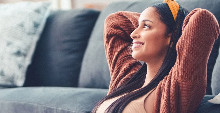 Smiling woman leaning against sofa