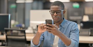 African American man using smartphone in office