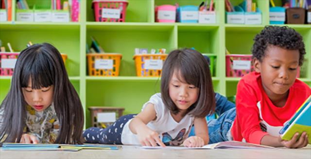 Young children laying on floor reading.