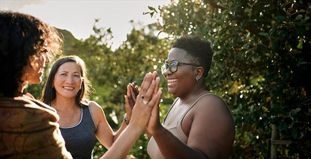 Small group of racially diverse women smiling while exercising outdoors.
