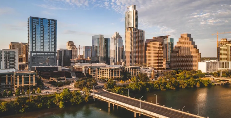 The image shows the downtown skyline of Austin, Texas, viewed from the south across Lady Bird Lake