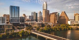 The image shows the downtown skyline of Austin, Texas, viewed from the south across Lady Bird Lake
