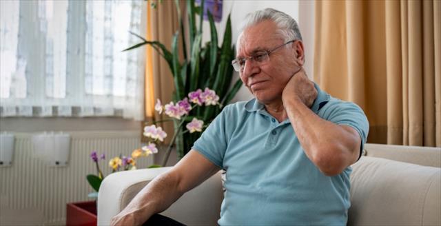 Elderly man touches the back of his neck