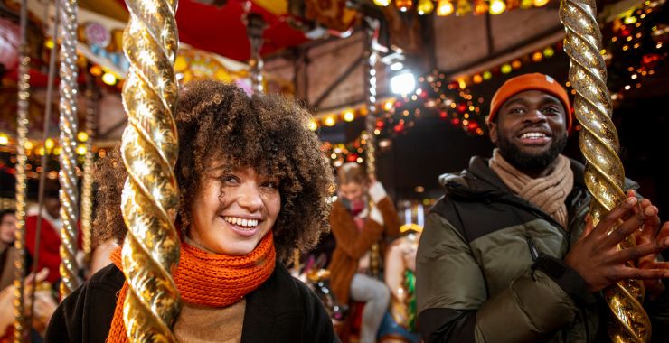 Two friends on a merry-go-round enjoying the festive fun at a Christmas market