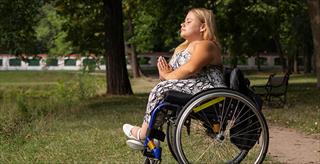 Young woman meditates while sitting in her wheelchair.