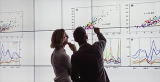 two people looking and pointing at notes written on a large white board