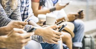 Close crop on people sitting together with cell phones in their hands