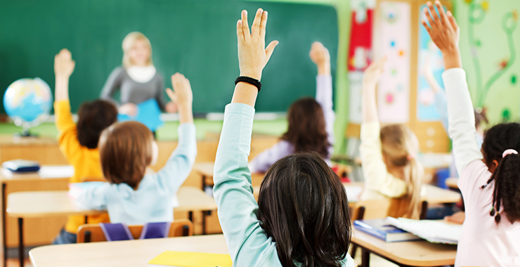 Young students raising their hands to speak in class.
