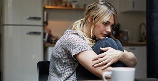 Woman sitting down and hugging her knees