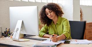 person at desk writing on paper