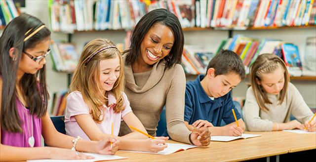 Teacher smiling with elementary students taking a test