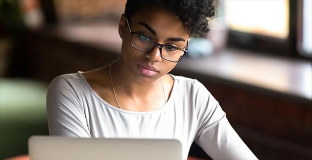 Biracial girl in glasses studying on laptop.