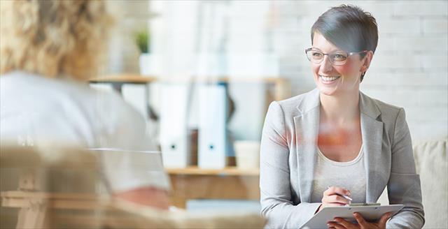 Psychologist sitting across from patient and smiling with notepad in hand