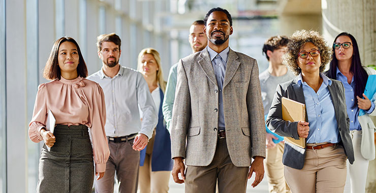 Diverse group of young professionals walking together down a hallway.