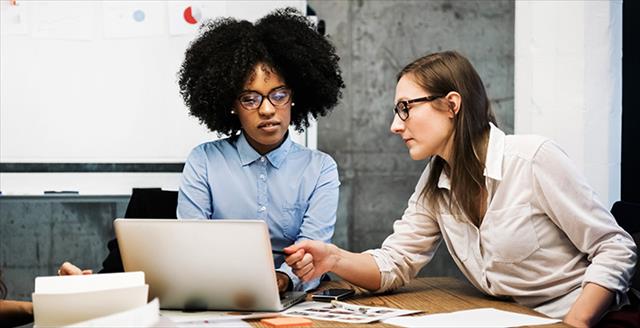 Two women looking at a laptop in a work setting