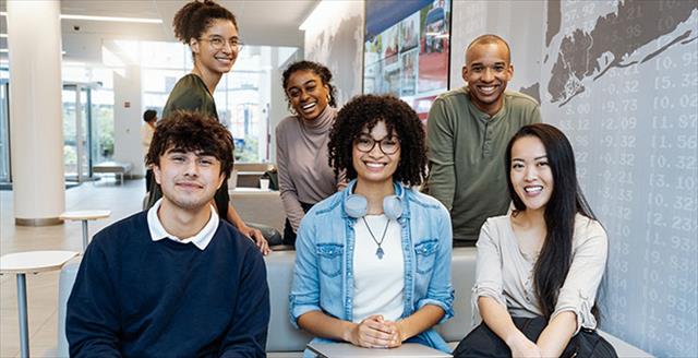 Diverse group of high school students seated on couch, smiling at camera.