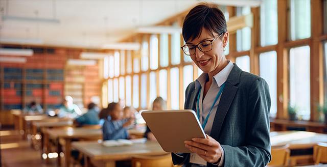 Teacher uses smart tablet while class works on assignment.