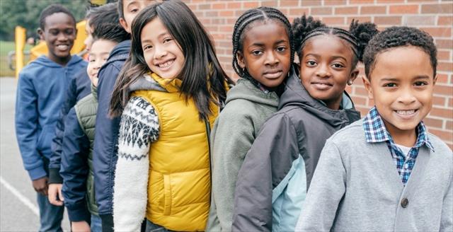 School children stand in a line outside of the school