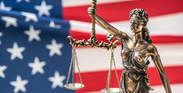 statue of blind justice in front of American flag