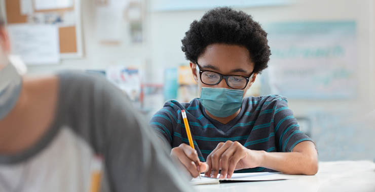 Middle school student with glasses writing in notebook