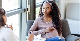 Expectant young woman listens to unrecognizable female counselor