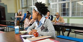 Girl sitting by herself in cafeteria.