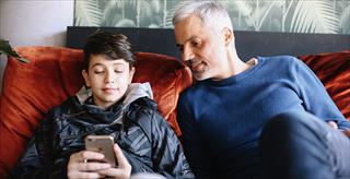 Father and young teen son looking at smartphone