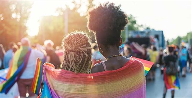 Young female couple hugging with rainbow scarf at the pride event