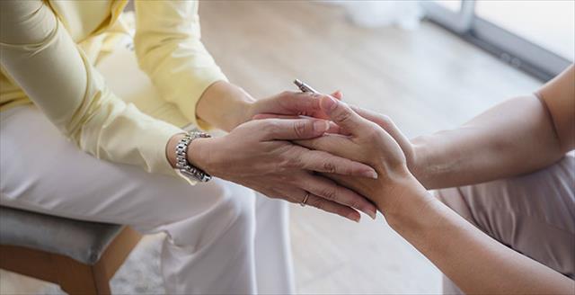 Close-up of female psychologist hands holding to her patient man at the counseling room