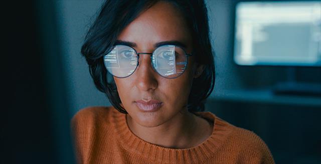 Female computer programmer works on complex software development tasks at her home office late into the night