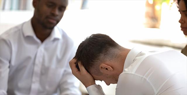 Diverse people during group therapy focus on desperate caucasian guy