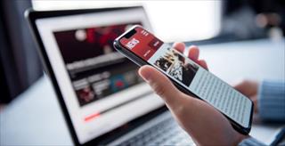 Woman reading news or articles in a mobile phone screen application at home.