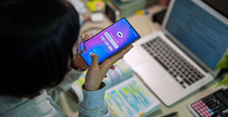 Student using AI app on smartphone to complete coursework.
