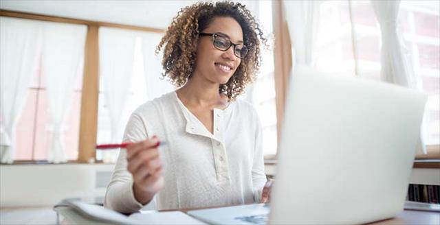 Student working on a laptop in a bright, sunny room that matches her disposition