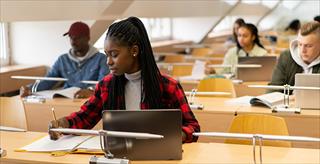 Very focused students individually working in a sunlit minimalist library space