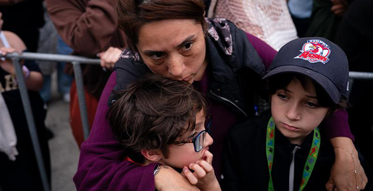 A young girl holding a teddy bear being comforted by her dad.