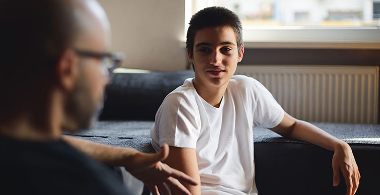 Older adult man speaking to teen boy.
