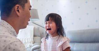 Preschool aged girl crying in front of dad