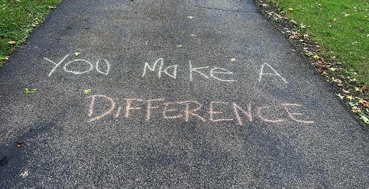 Chalk message reading “You Make A Difference” written on a paved pathway.